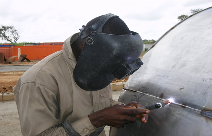 Welder working on stainless steel tank shell